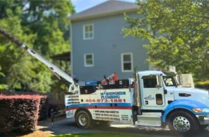 A plumbing truck parked on a residential street boasts tools for trenchless sewer line installs. The side of the truck displays the company name, phone number, and various services offered in Conyers.